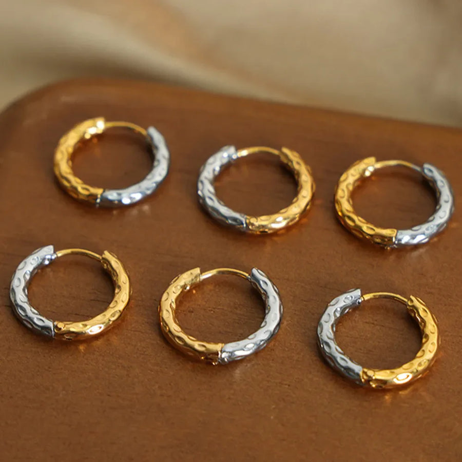 Textured two-tone huggie hoop earrings in gold and silver with a hammered finish.