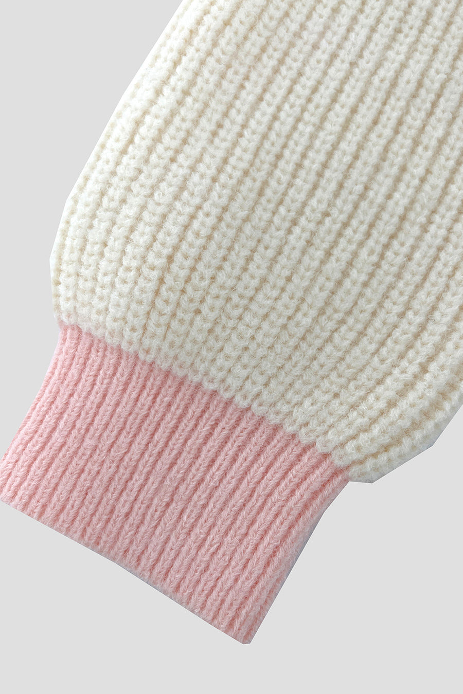Cream acrylic knit cardigan with pink contrast trim on the cuff.