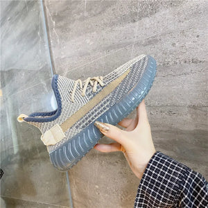 Textured knit platform sneakers in light gray with tan stripe detail and blue trim.
