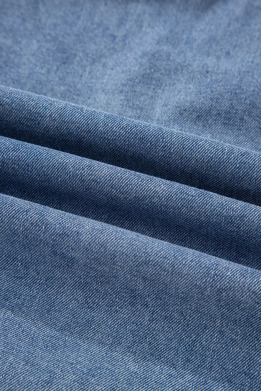V-shaped pleated denim sleeveless top in blue denim with a textured weave.