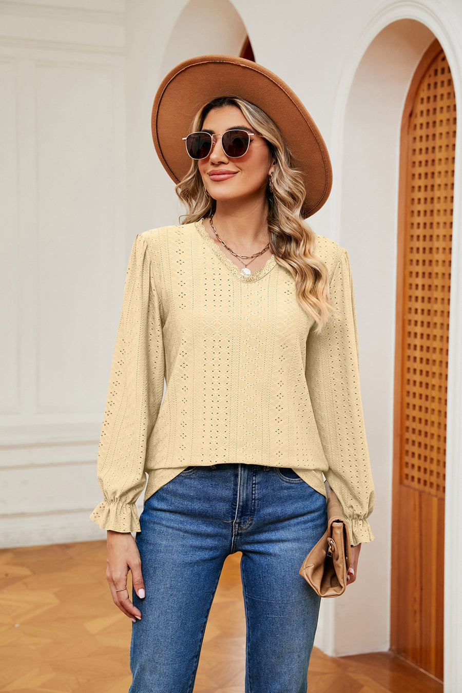 Pastel yellow perforated blouse with v-neck and ruffle cuffs.