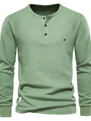 Matcha green waffle knit henley top with raglan sleeves and button placket.