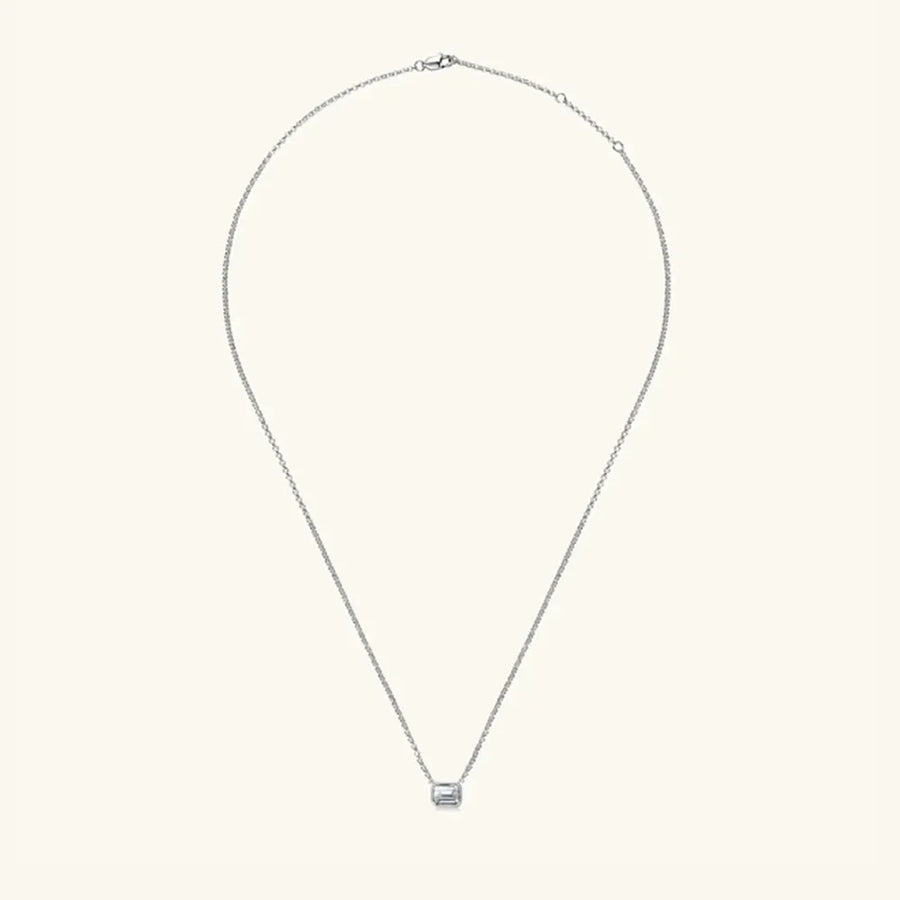 Silver necklace with emerald cut moissanite solitaire pendant and gold bezel.