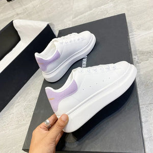 White platform sneakers with light purple suede heel detail and white laces.