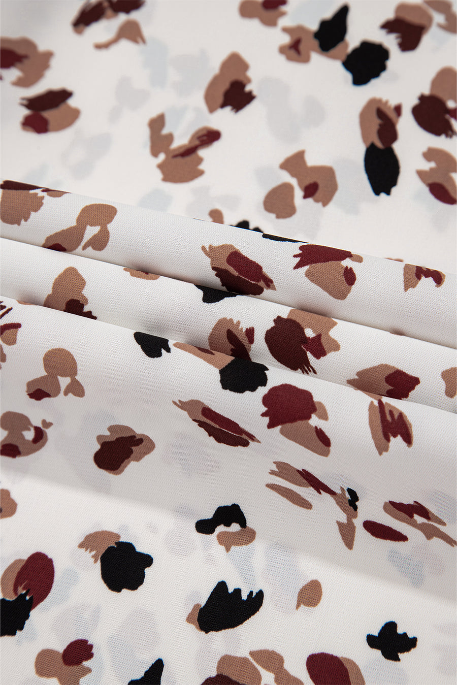 White abstract print blouse with a high neck, featuring a scattered animal-like pattern.
