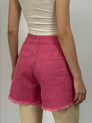 Fuchsia pink high-rise denim shorts with frayed hem and rhinestone embellishments.