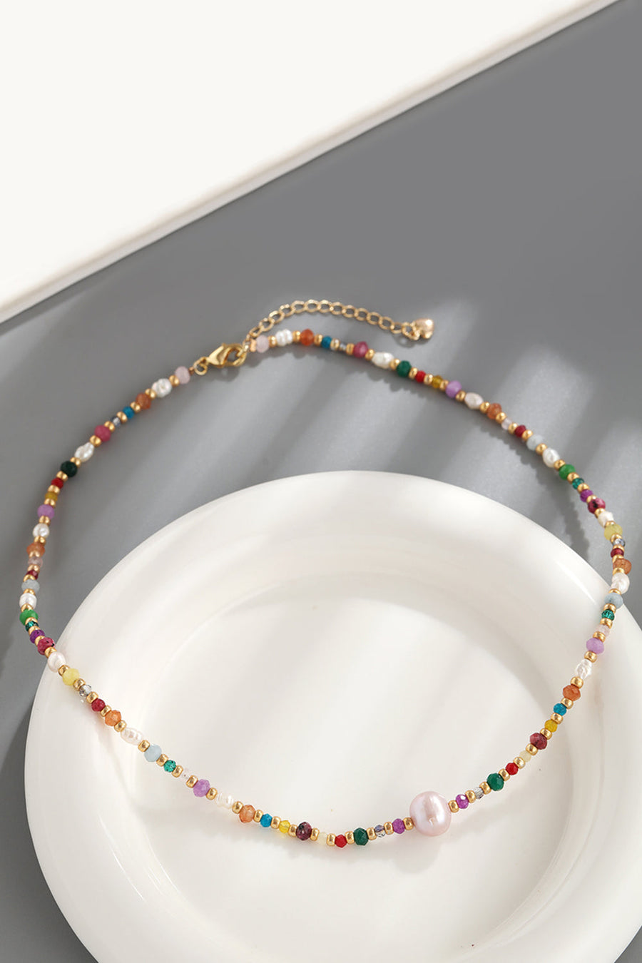 Multicolor beaded gemstone and pearl necklace with gold chain and clasp.