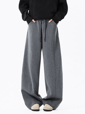 Men's dark gray drawstring wide leg sweatpants with pockets and stitched seams.