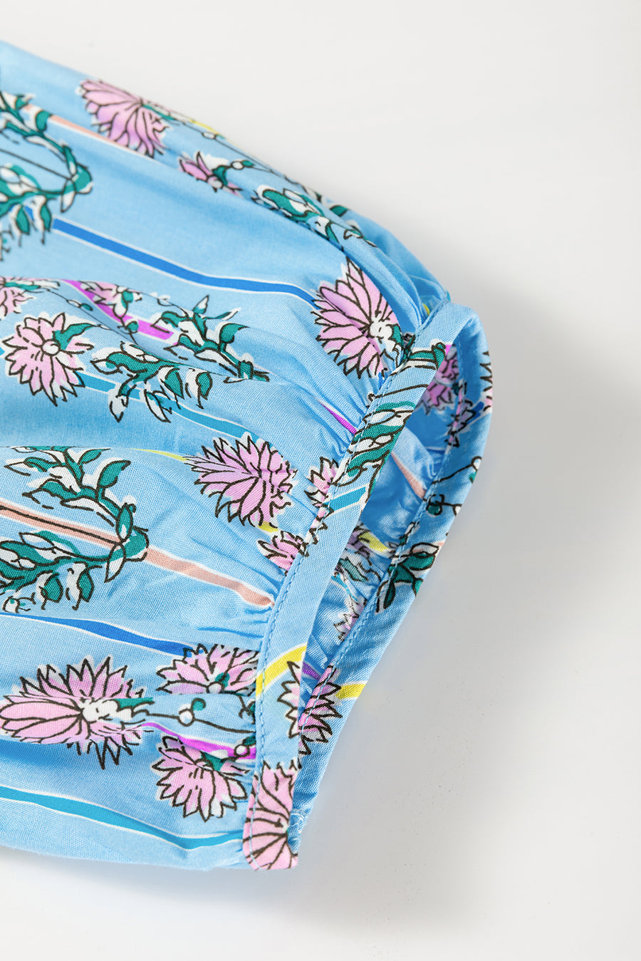 Sky blue floral print smocked yoke blouse with ruffled cuffs and striped accents.