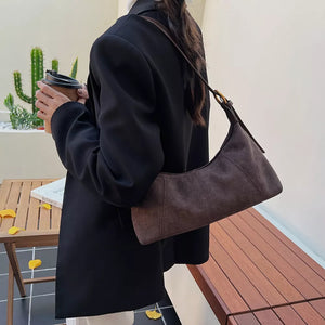 Chic suede crescent shoulder bag in coffee brown with adjustable strap.