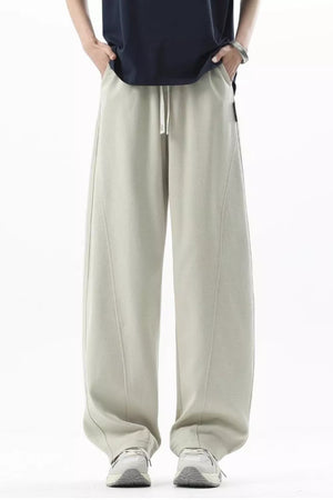 Men's beige loose fit sweatpants with drawstring and curved seam details.