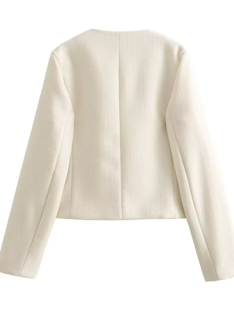 White cropped tweed button-up jacket with a round neckline and long sleeves.