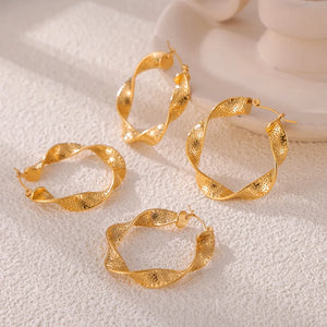 Gold textured spiral hoop earrings with a twisted design and subtle dot pattern.