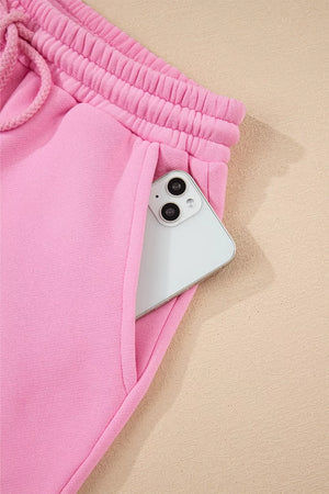 Pink cotton sweat shorts with drawstring waist and phone in pocket.