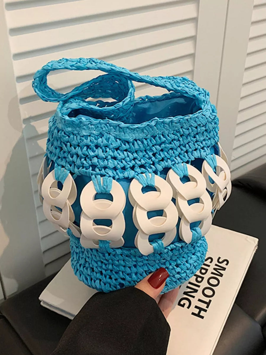 Blue woven straw bucket tote with white ring embellishments and braided strap.