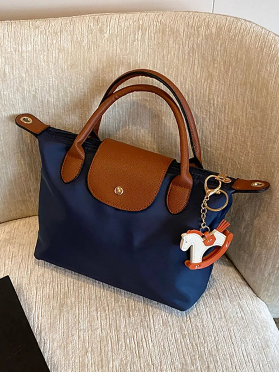 Navy nylon tote bag with brown leather accents and a rocking horse charm