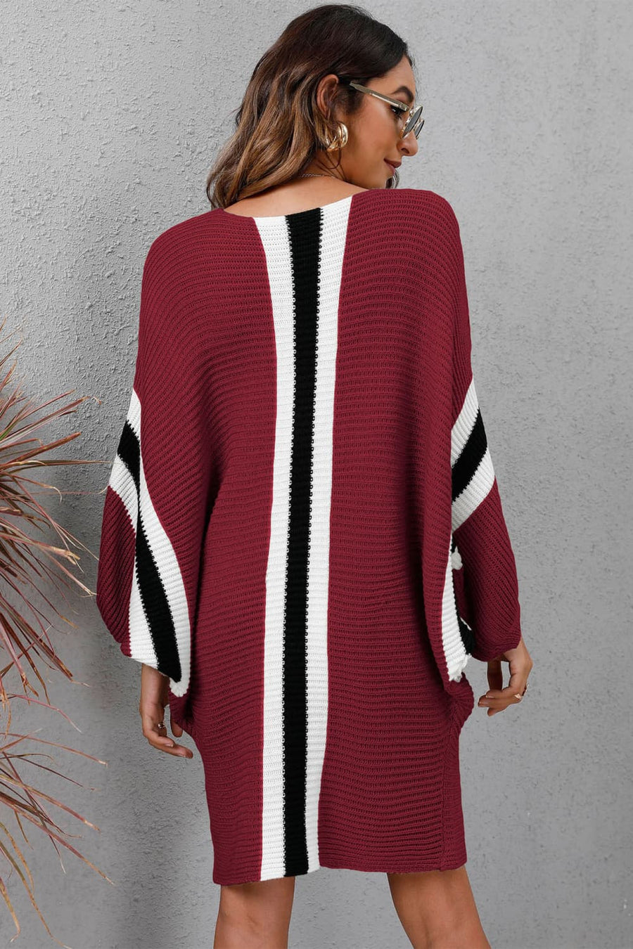 Burgundy knit cocoon dress with white and black stripe details on sleeves and back.