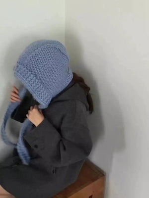 Blue wool earflap beanie hat with chunky knit and ties.