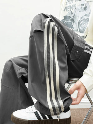 Oversized cargo pants in dark gray with white side stripes and flap pockets.