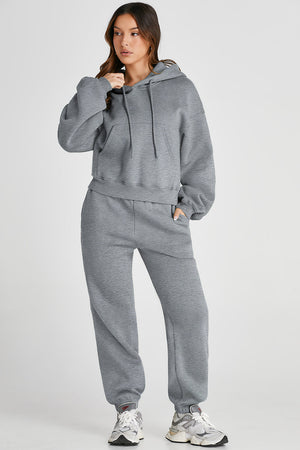 Gray relaxed fit loungewear set with hoodie and pockets, and matching sweatpants.