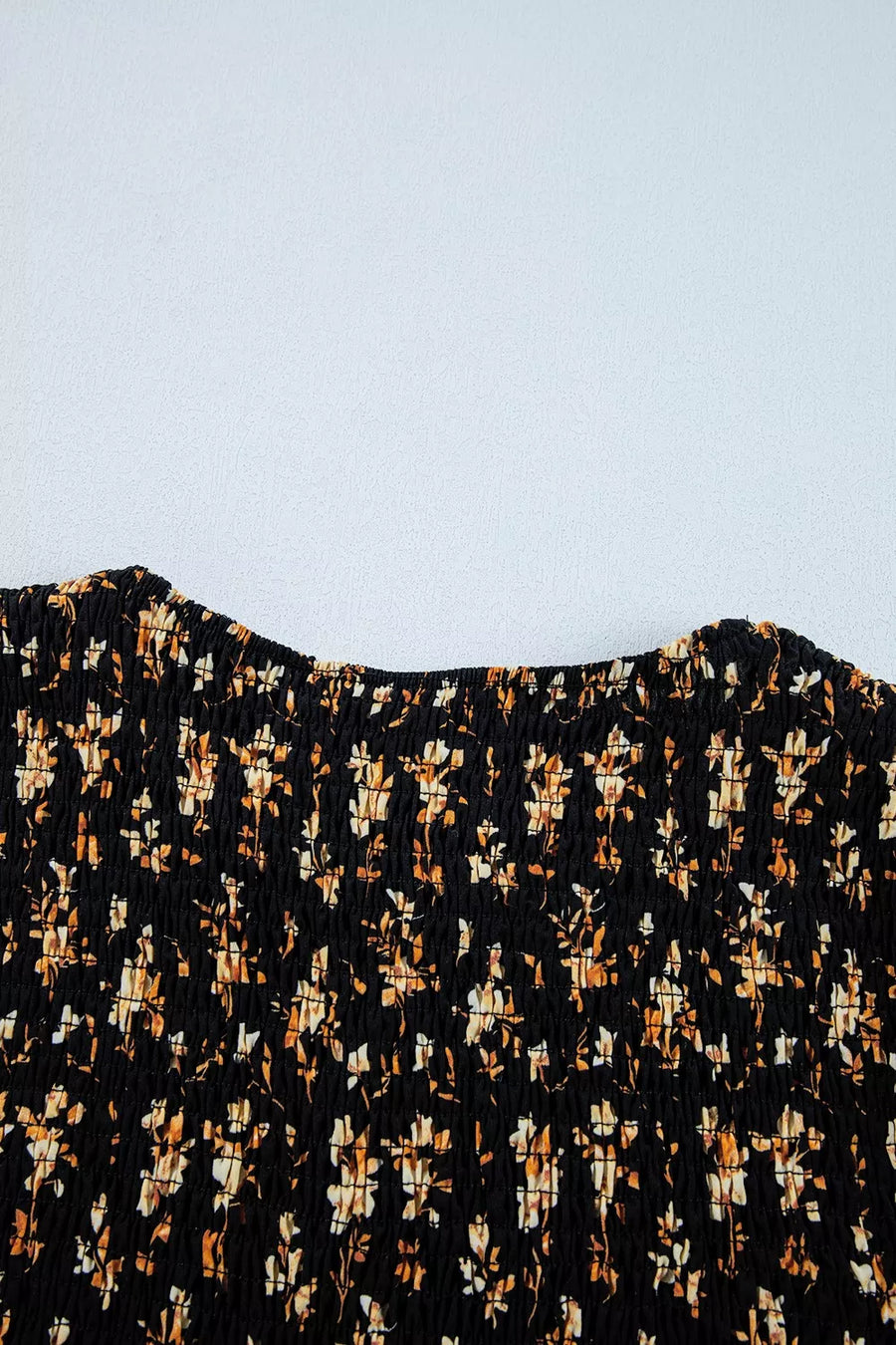 Black floral smocked blouse with a square neckline and long sleeves.