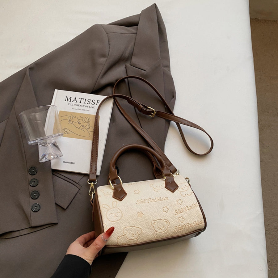 Mini crossbody bag in beige with cartoon bear and bunny pattern and brown trim.