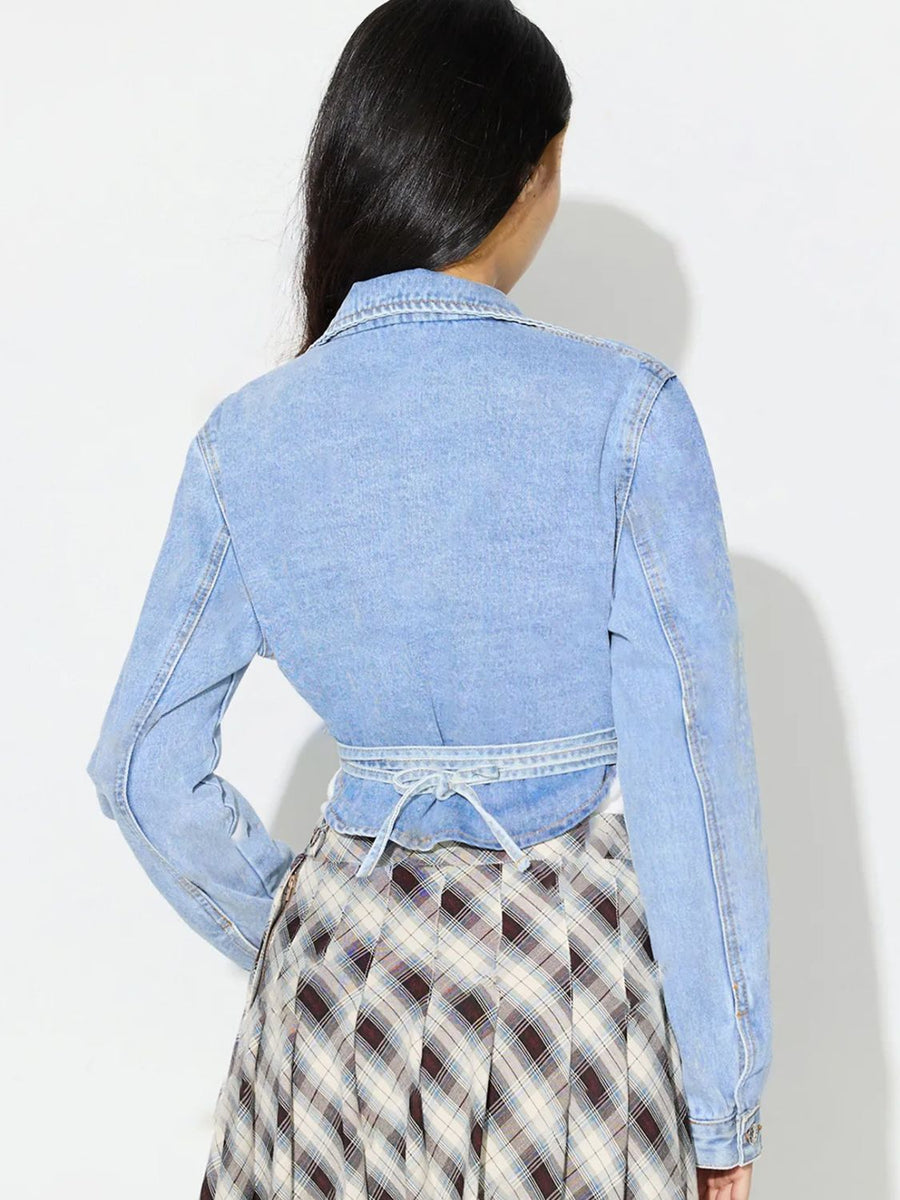 Medium wash denim wrap jacket with tie waist detail and asymmetric cut.