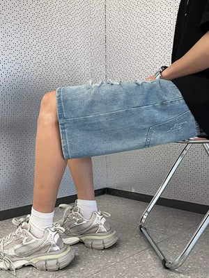 Men's light wash distressed denim shorts with wide leg and raw hem.