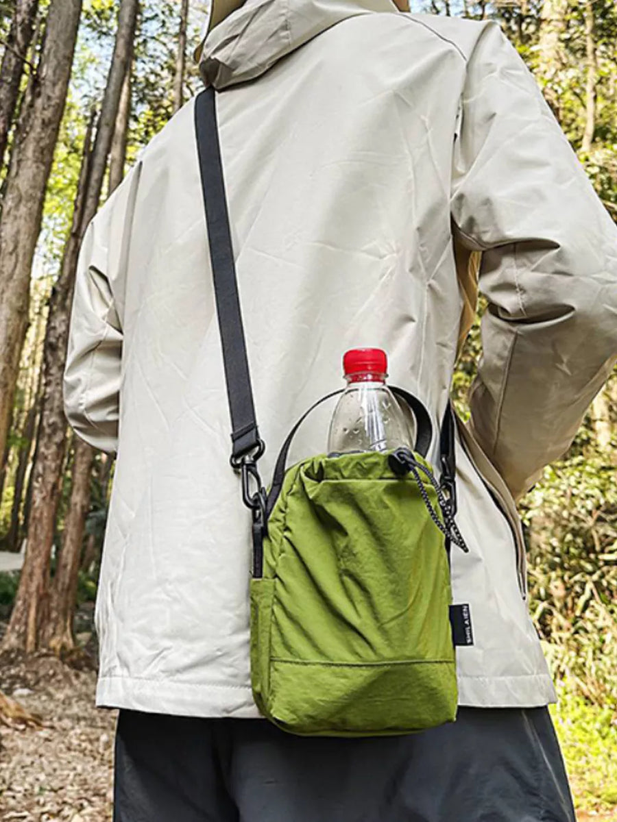 Green nylon drawstring shoulder bag with water bottle, worn crossbody.