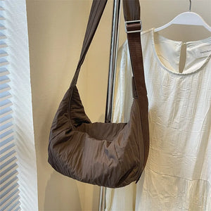 Quilted crescent shoulder bag in coffee brown with adjustable strap.