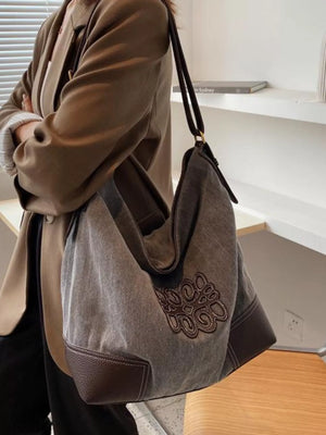 Medium canvas tote bag in grey with brown leather trim and embroidered detail.