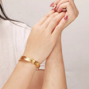 Gold bracelet featuring open cuff and textured