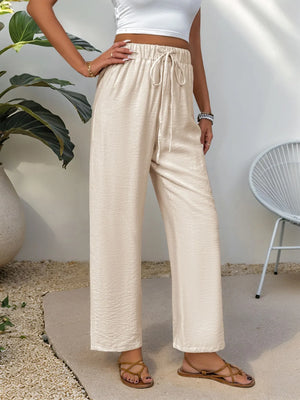 Chic tan waist-tie flare trousers with a textured fabric and relaxed fit.
