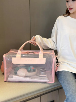Chic transparent pink PVC travel bag with pink trim and handles, showing toiletries inside.