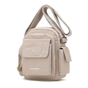Off-white lightweight nylon crossbody bag with multiple pockets and adjustable strap