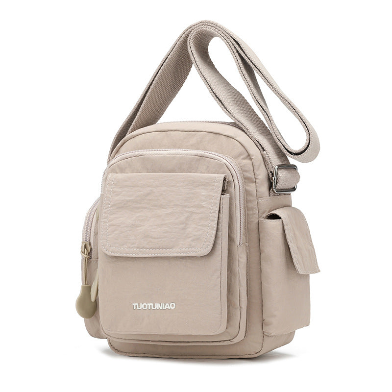 Off-white lightweight nylon crossbody bag with multiple pockets and adjustable strap