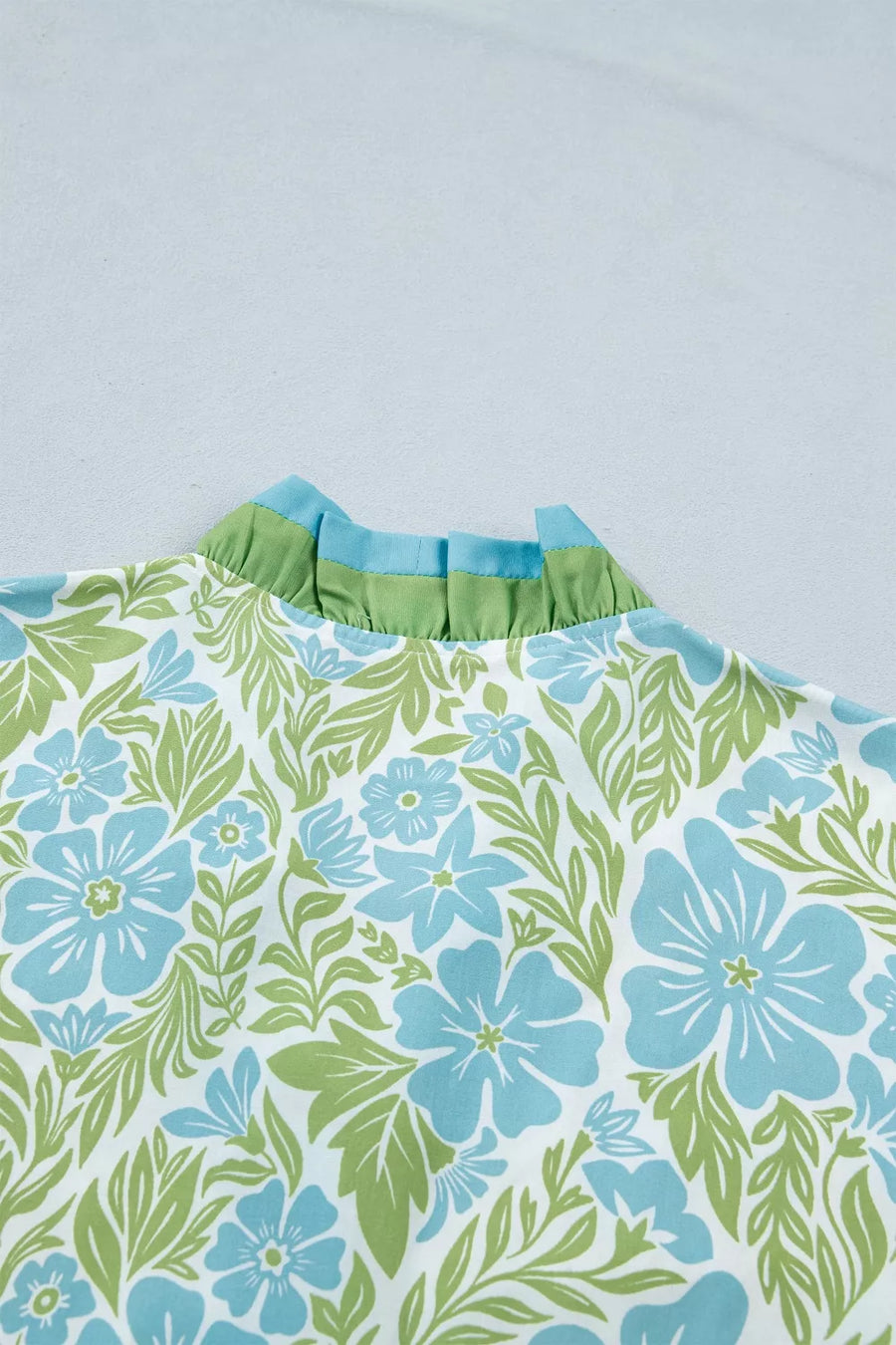 Mini dress with blue floral print, green leaves, and ruffled collar detail.