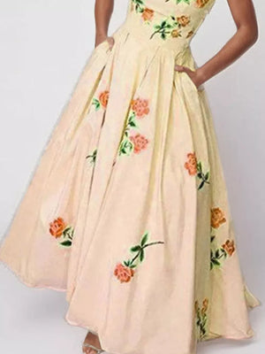Floral print tube maxi dress in blush pink with orange roses and green leaves, featuring pockets.