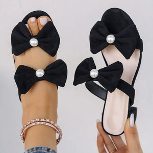 Black bow block heel mules with pearl embellishments.