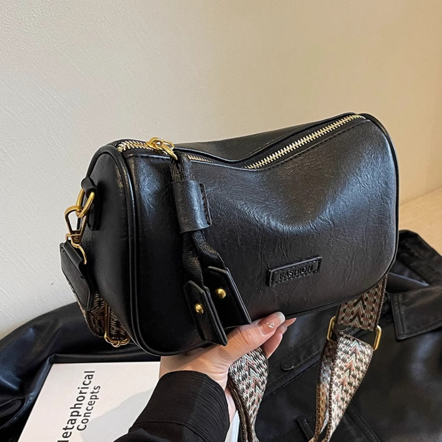 Black textured pu leather crossbody bag with a patterned strap and tassel detail.