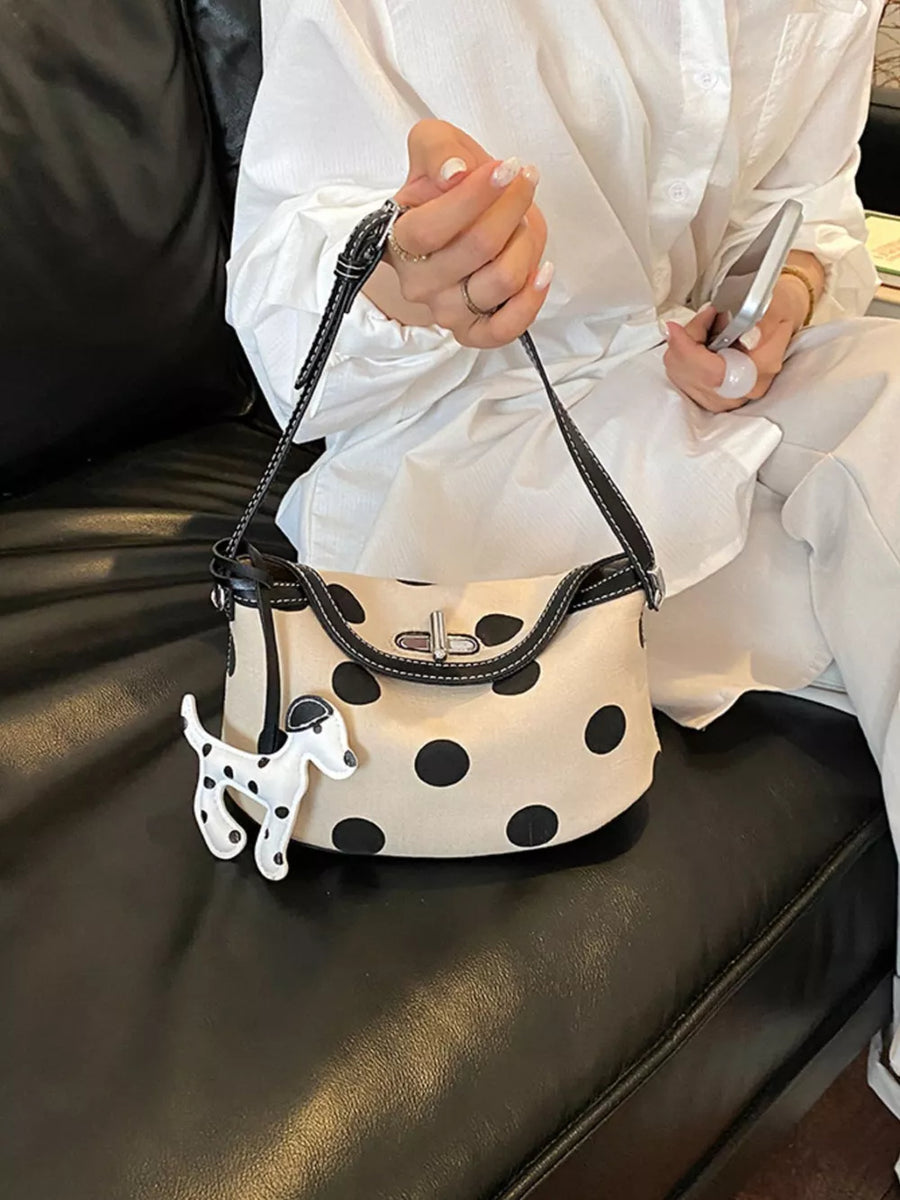 black shoulder bag featuring flap closure and polka-dot