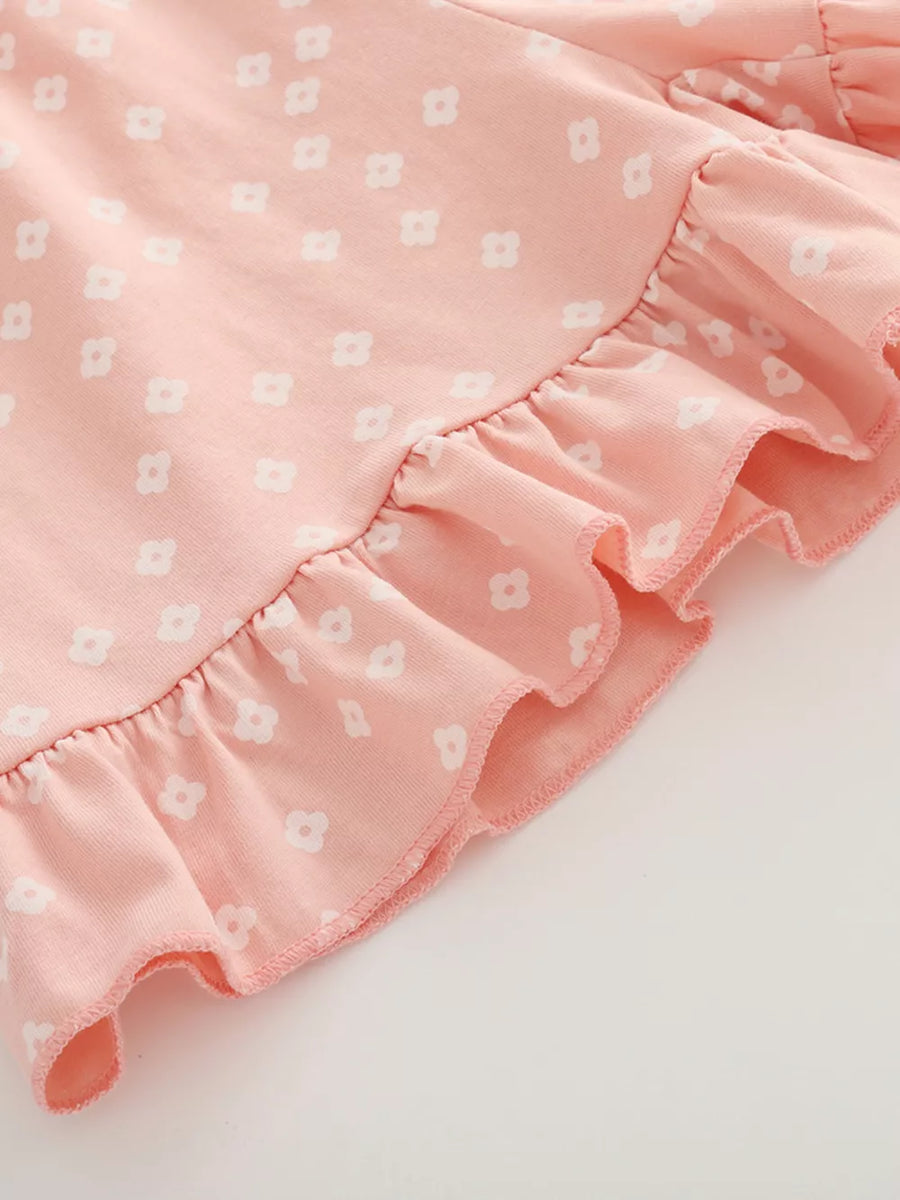 Pink cotton tee with white floral print and ruffled hem detail.