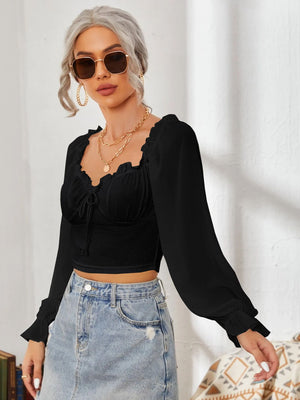 Black bustier blouse with sweetheart neckline, tie front, and ruffled long sleeves.
