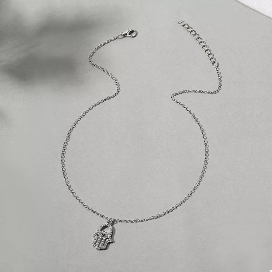 Silver chain necklace with a rhinestone hamsa hand pendant.