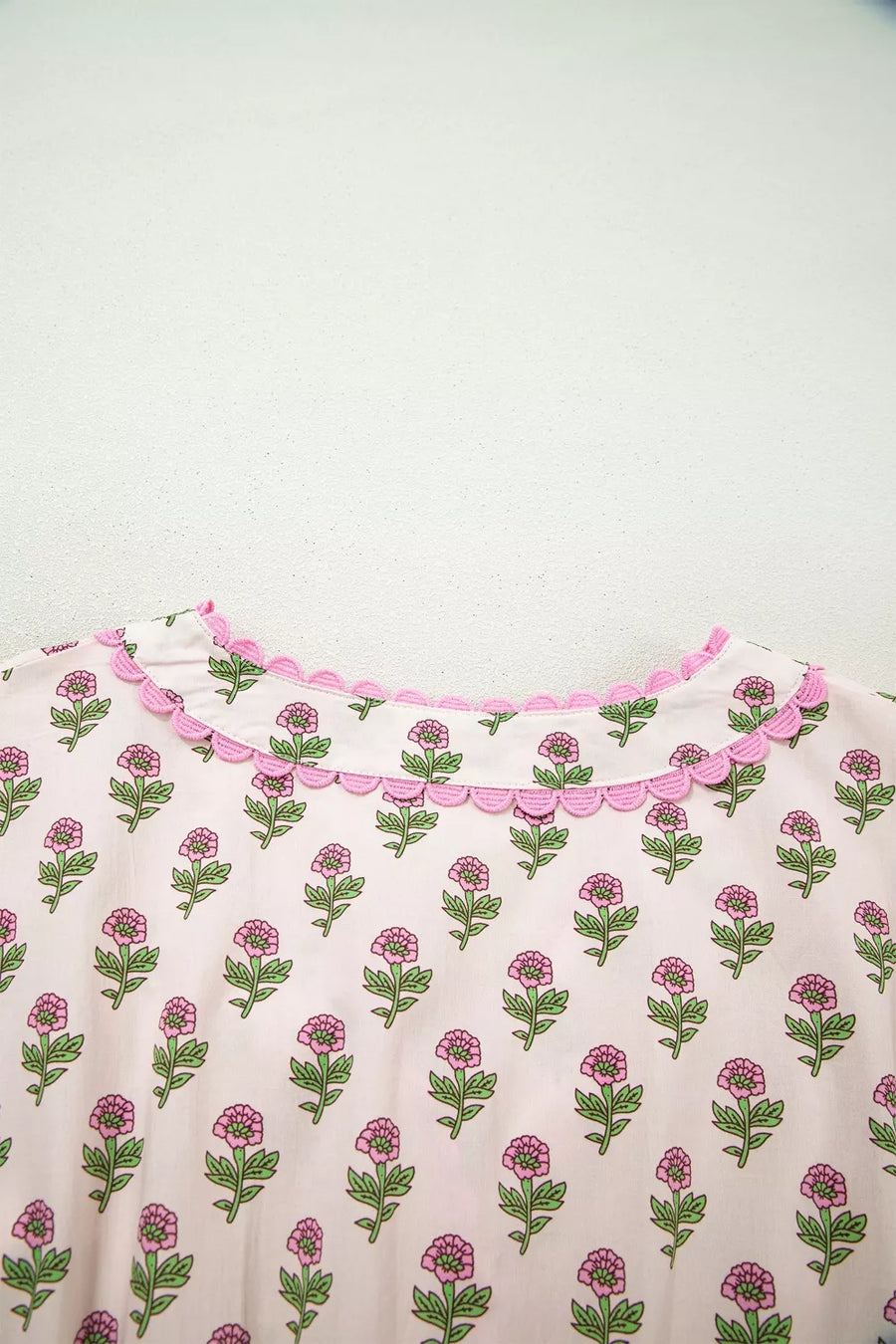 Floral v-neck midi dress in blush pink with scalloped trim and button front detail.