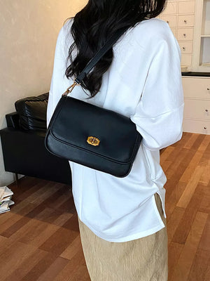 shoulder bag in black featuring flap closure and boxy fit