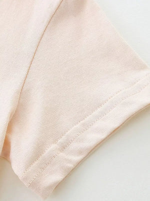 Baby dress sleeve detail in pale pink cotton with double-stitched hem.