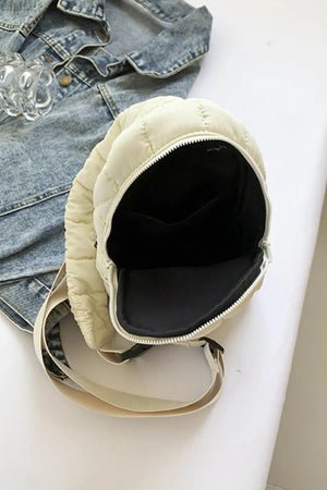 Padded sling bag in ivory with quilted detail and top handle, open to show interior.