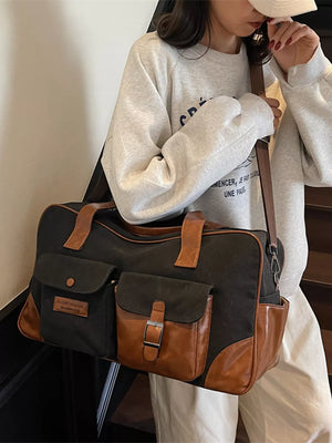Black canvas travel bag with brown leather accents and multiple pockets.