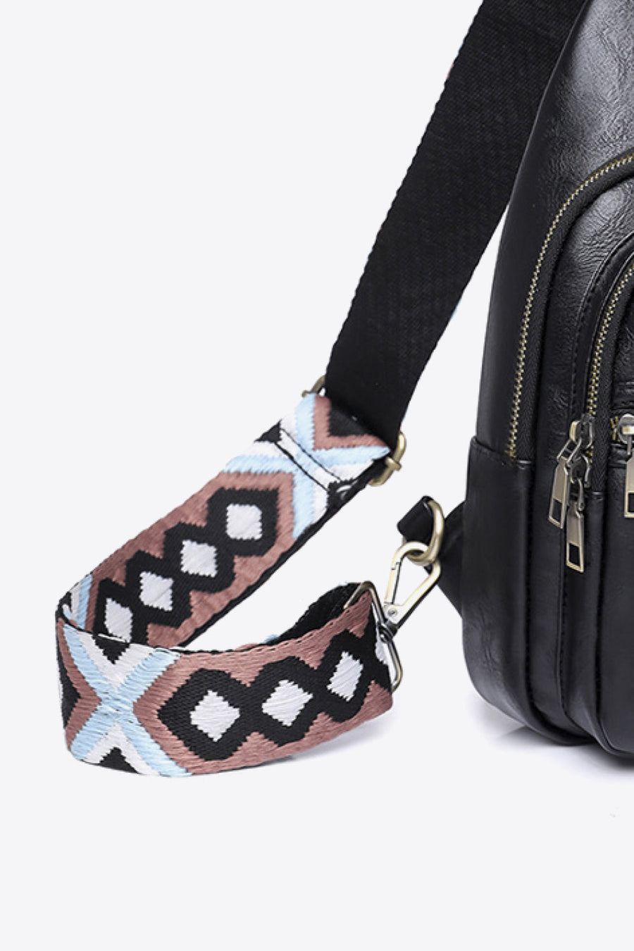Black crossbody bag with geometric patterned strap and silver hardware.